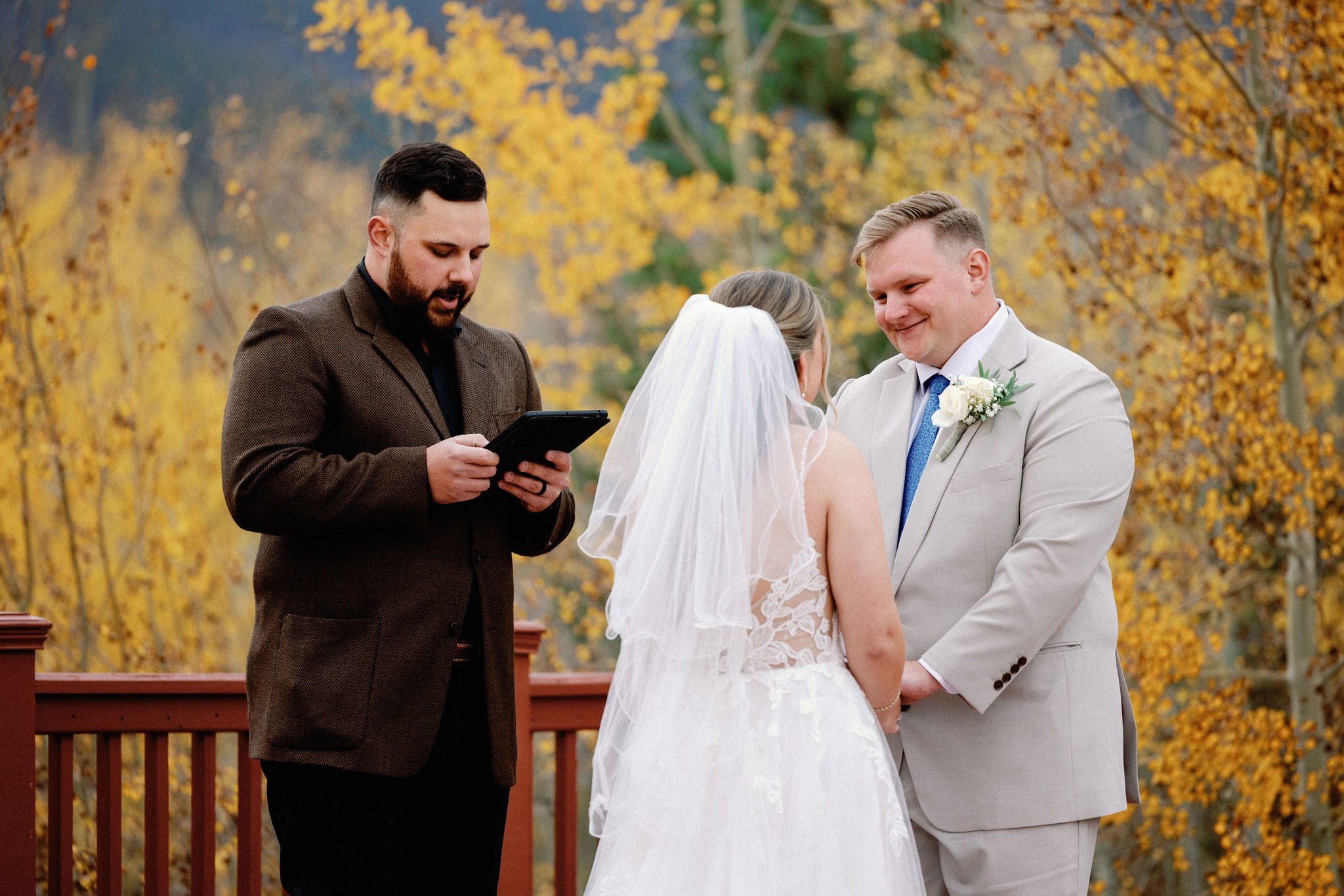 groom looks lovingly at bride while officiant reads for their micro wedding in colorado