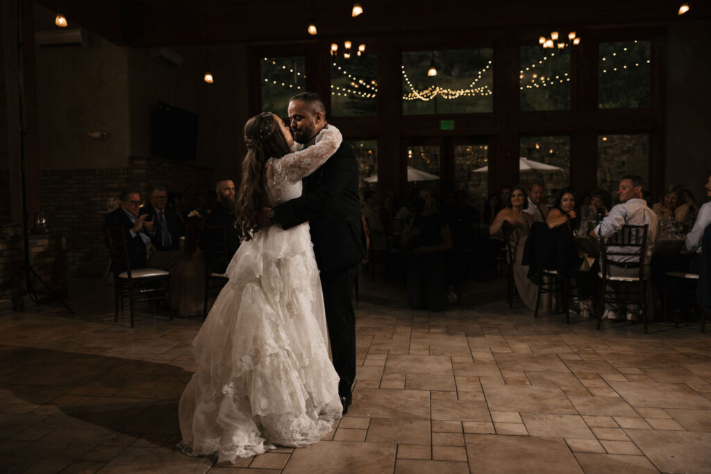 bride and groom kiss under twinkling lights during estes park micro wedding in colorado.