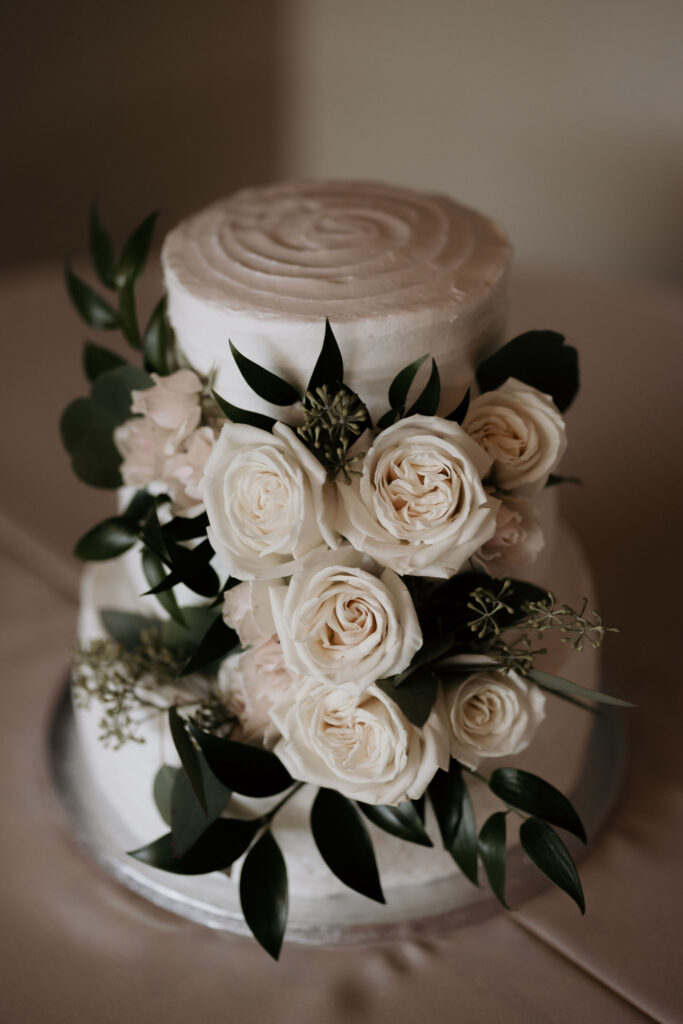 close up image of white cake with white roses during a colorado mountain wedding in estes park.