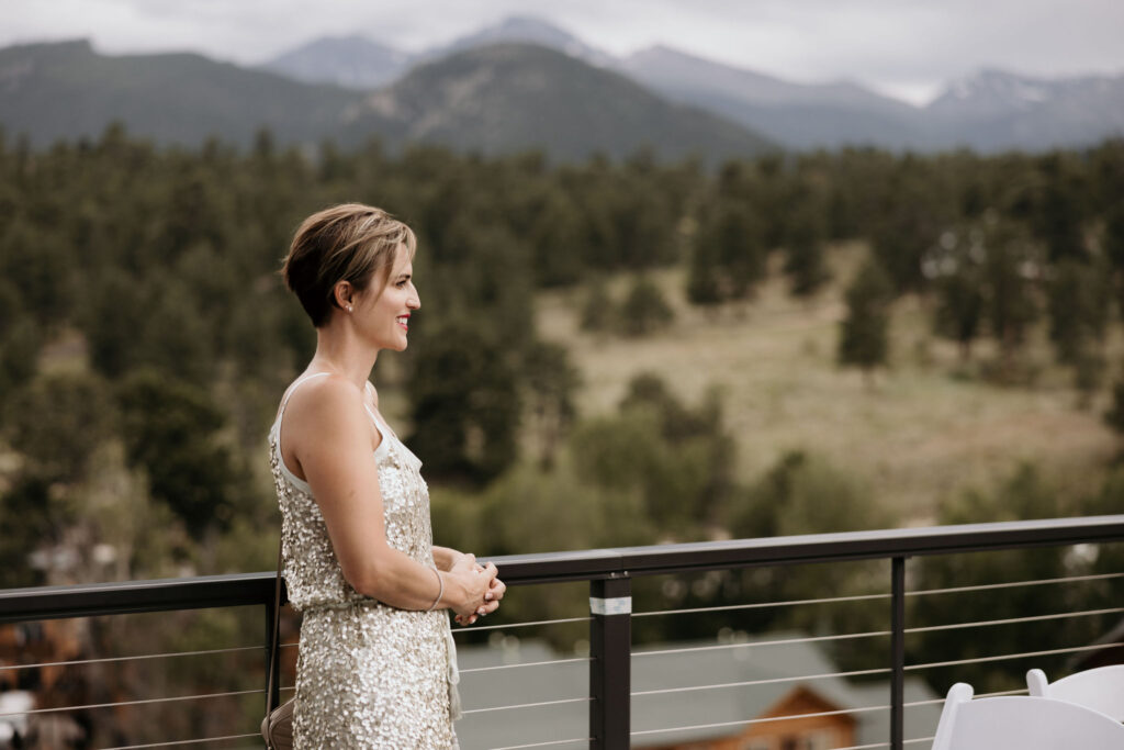 wedding guest stands on the deck during colorado mountain wedding in estes park.