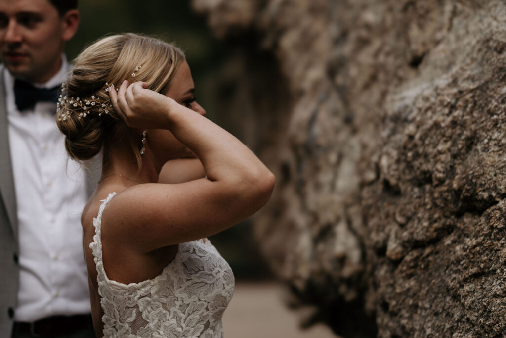 bride puts hair back and gets ready to climb rock during wedding at skyview venue in estes park.