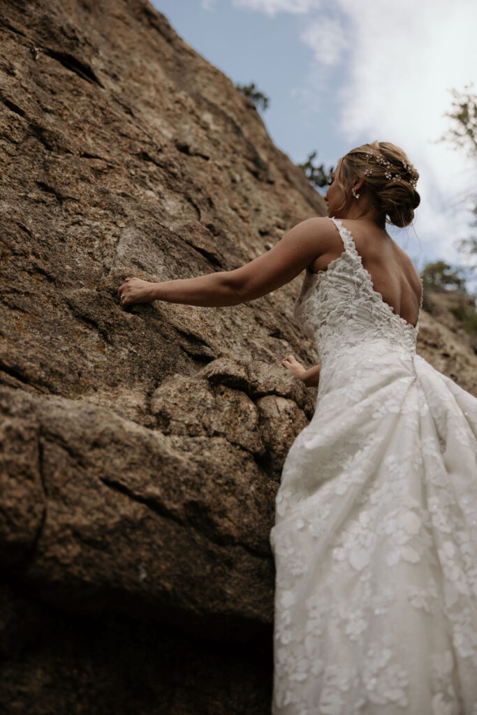 bride climbs rock during wedding at skyview venue in estes park.