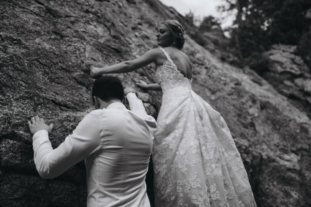 bride and groom climb rock during wedding at skyview venue in estes park colorado.