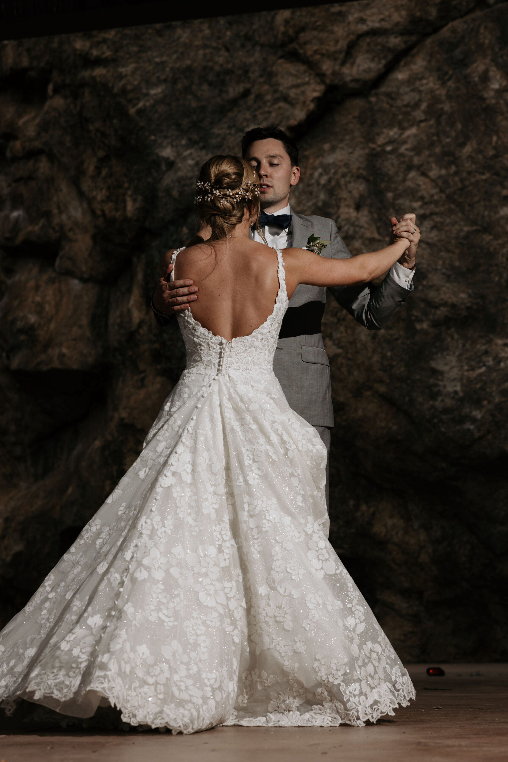 bride and groom dance by rock wall during colorado wedding at skyview venue in estes park.