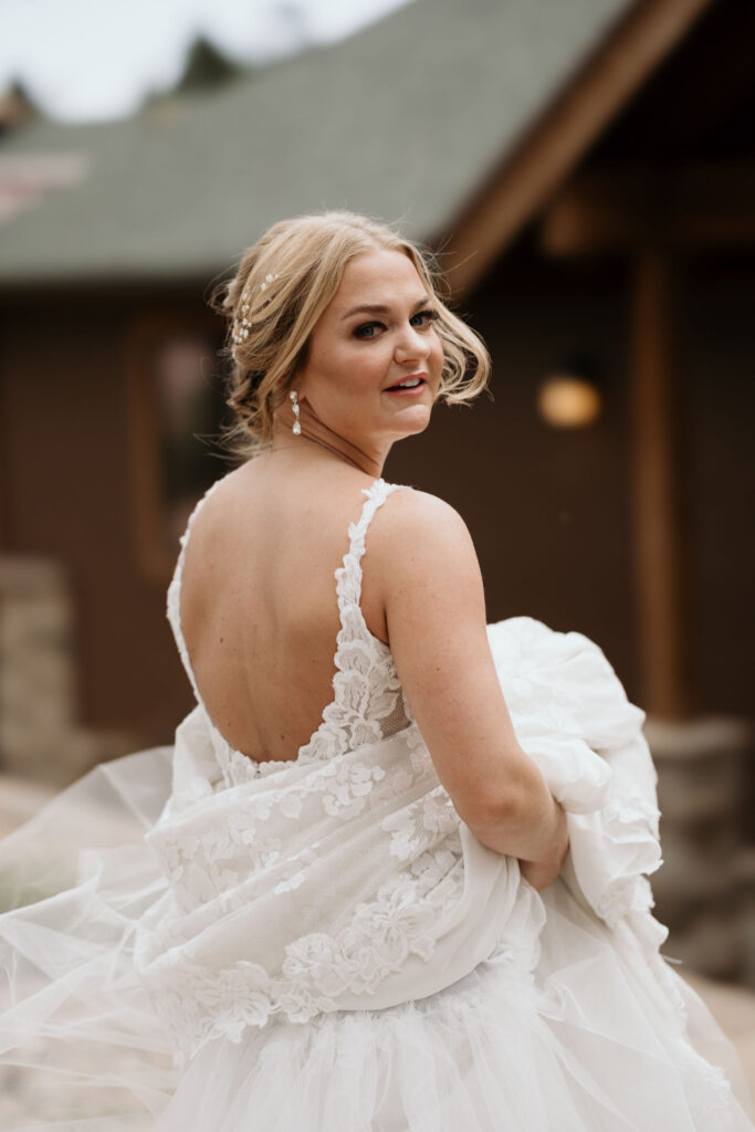 bride holds dress while preparing for first look at skyview wedding venue in estes park colorado.