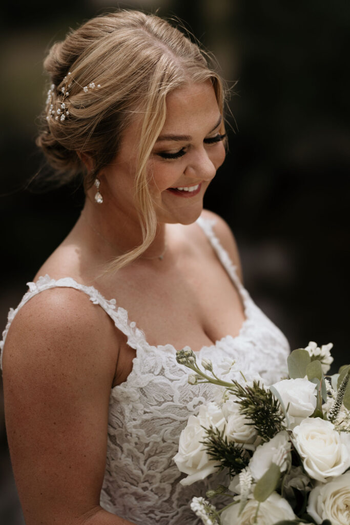 bride smiles and hold bouquet while preparing for first look at skyview wedding venue in estes park colorado.