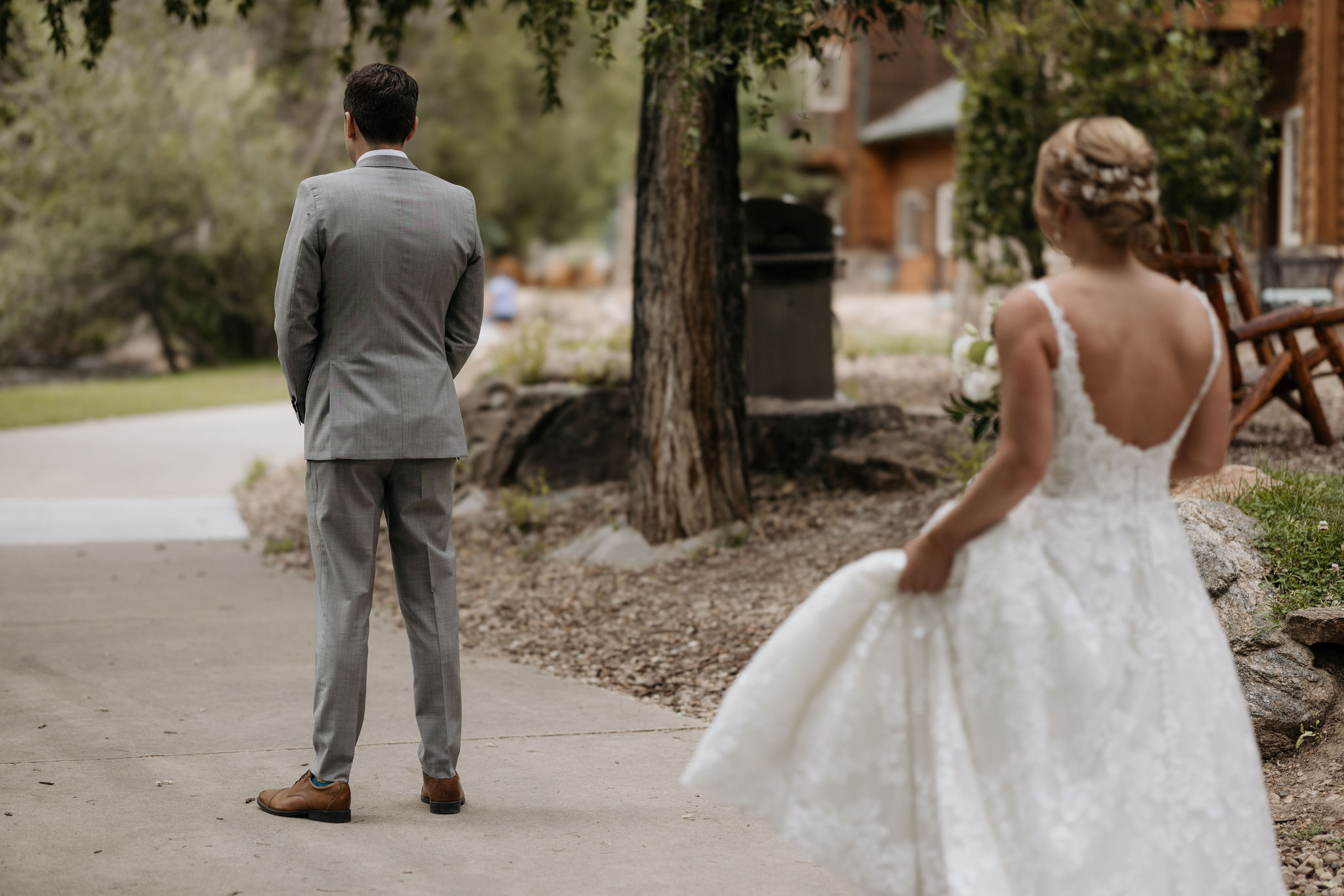 bride stands behind groom during their first look at skyview wedding venue in estes park colorado.