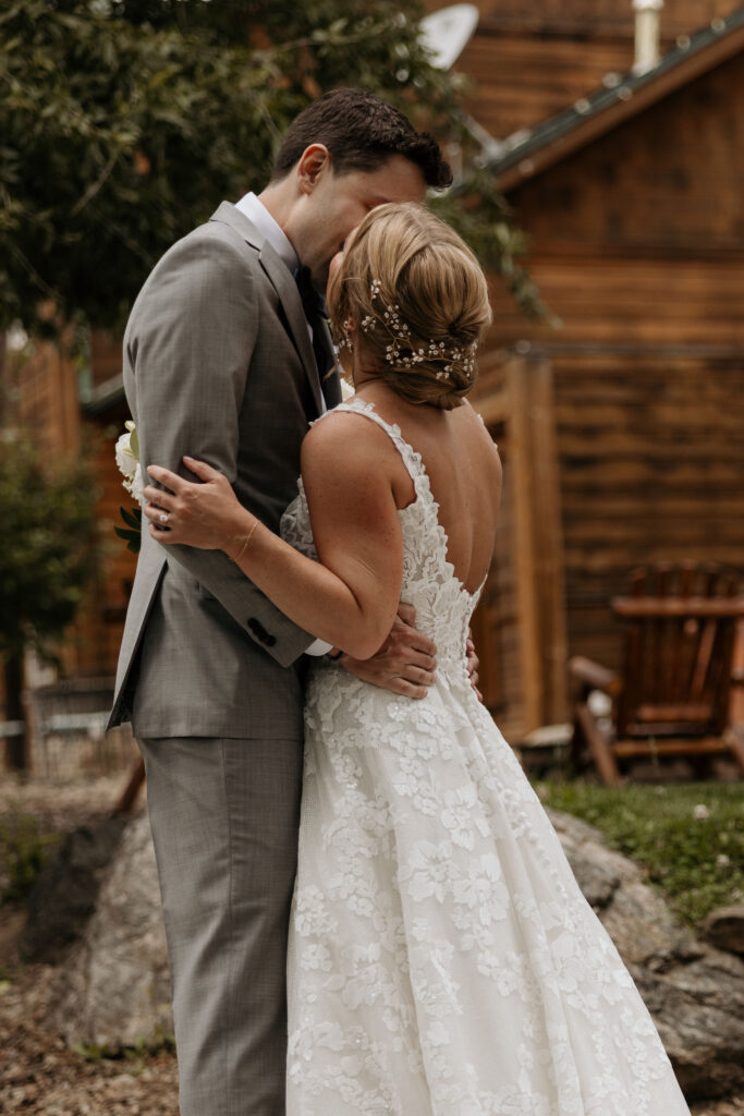 bride and groom kiss by river at skyview  for their colorado wedding in estes park.