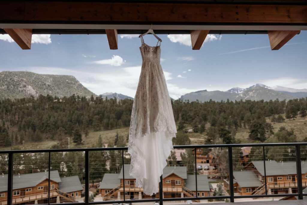wedding dress hangs with mountains in the background during a summer colorado wedding in estes park at the skyview venue.