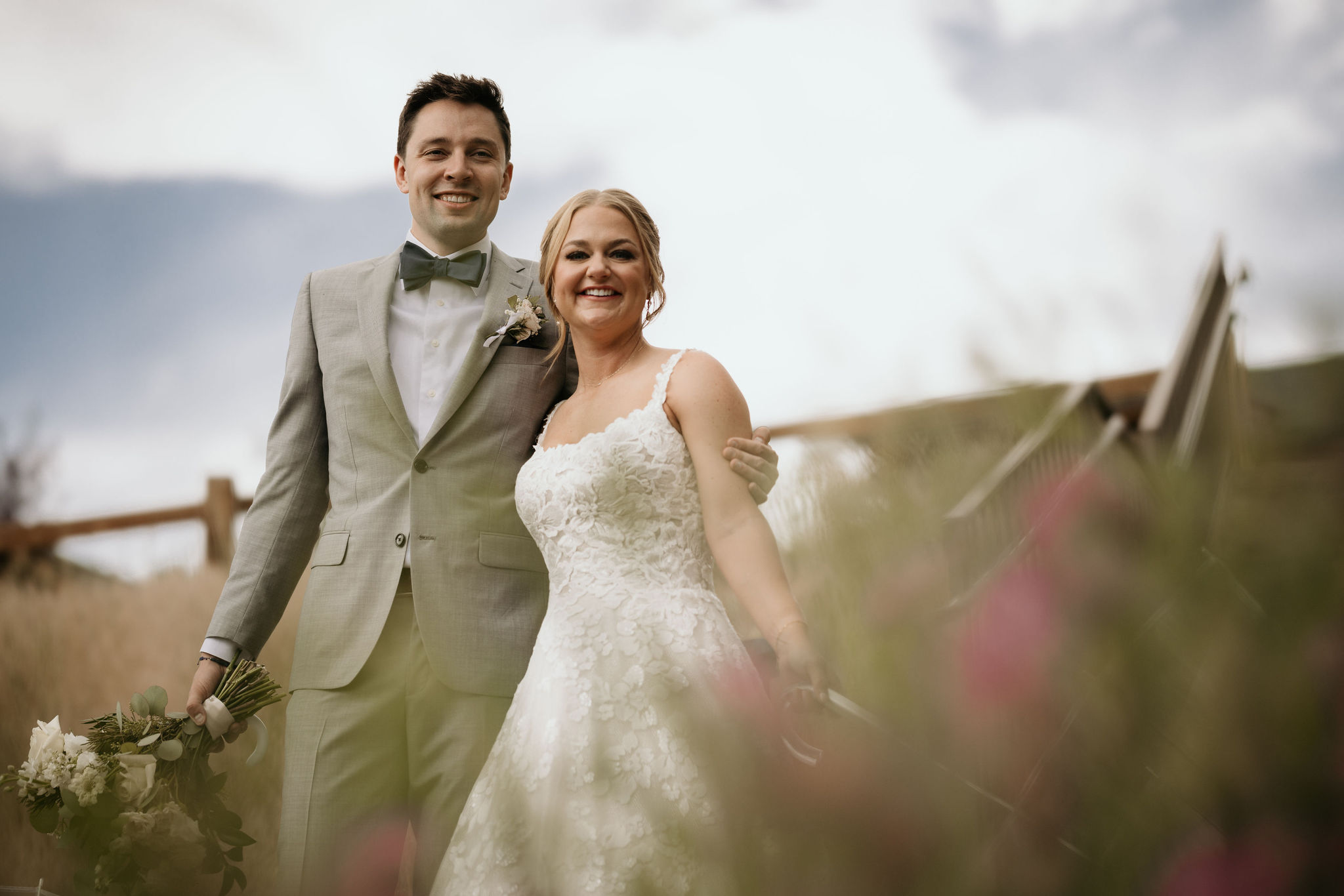 bride and groom stand on steps and smile during wedding portraits at skyview wedding venue in estes park colorado.