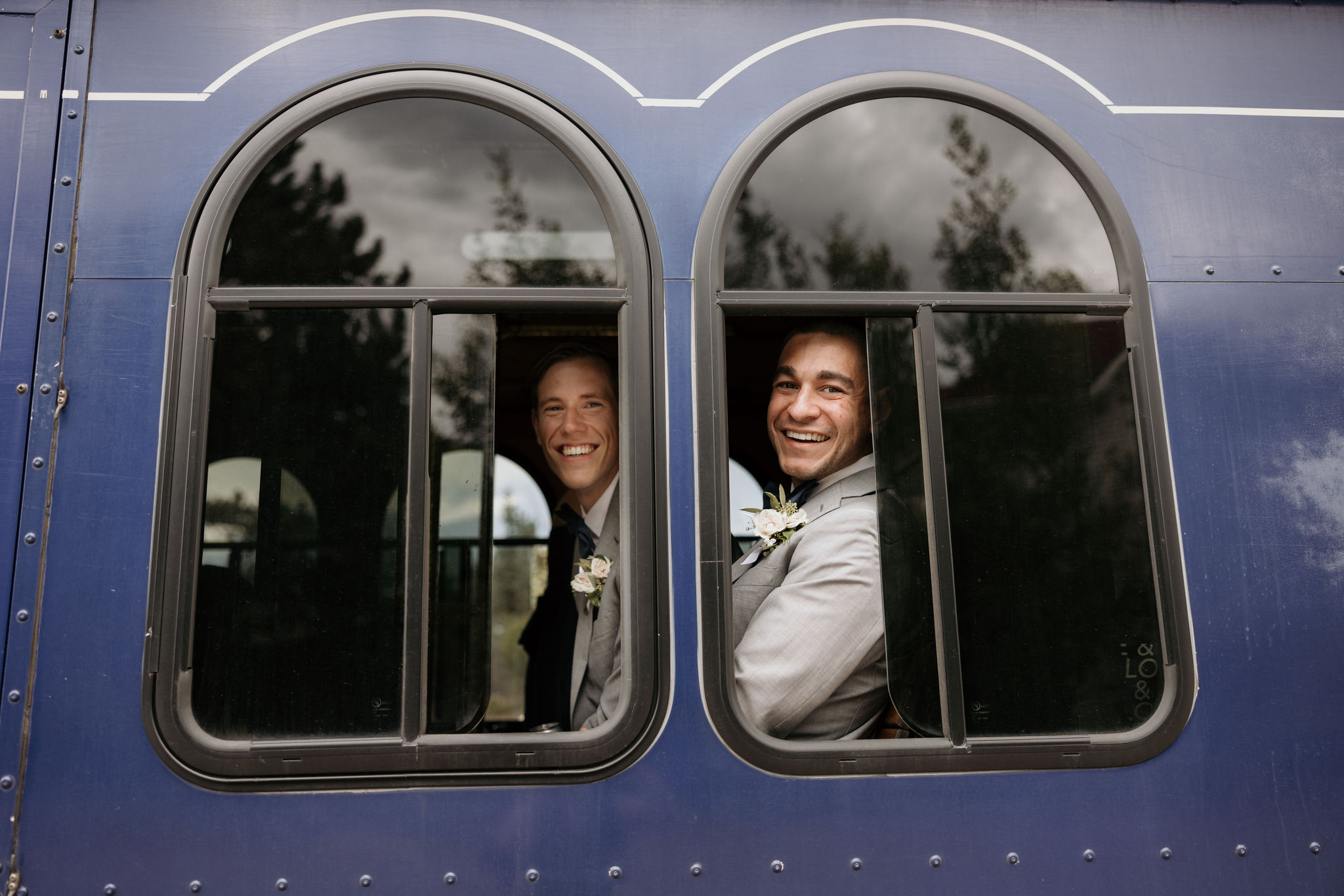 groomsman smile out vintage trolly window during colorado mountain wedding at skyview wedding venue.