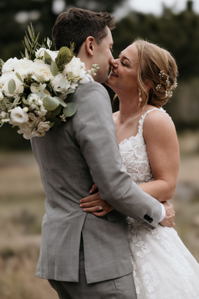 bride and groom embrace each other and go for a kiss during colorado wedding portraits in rocky mountain national park.