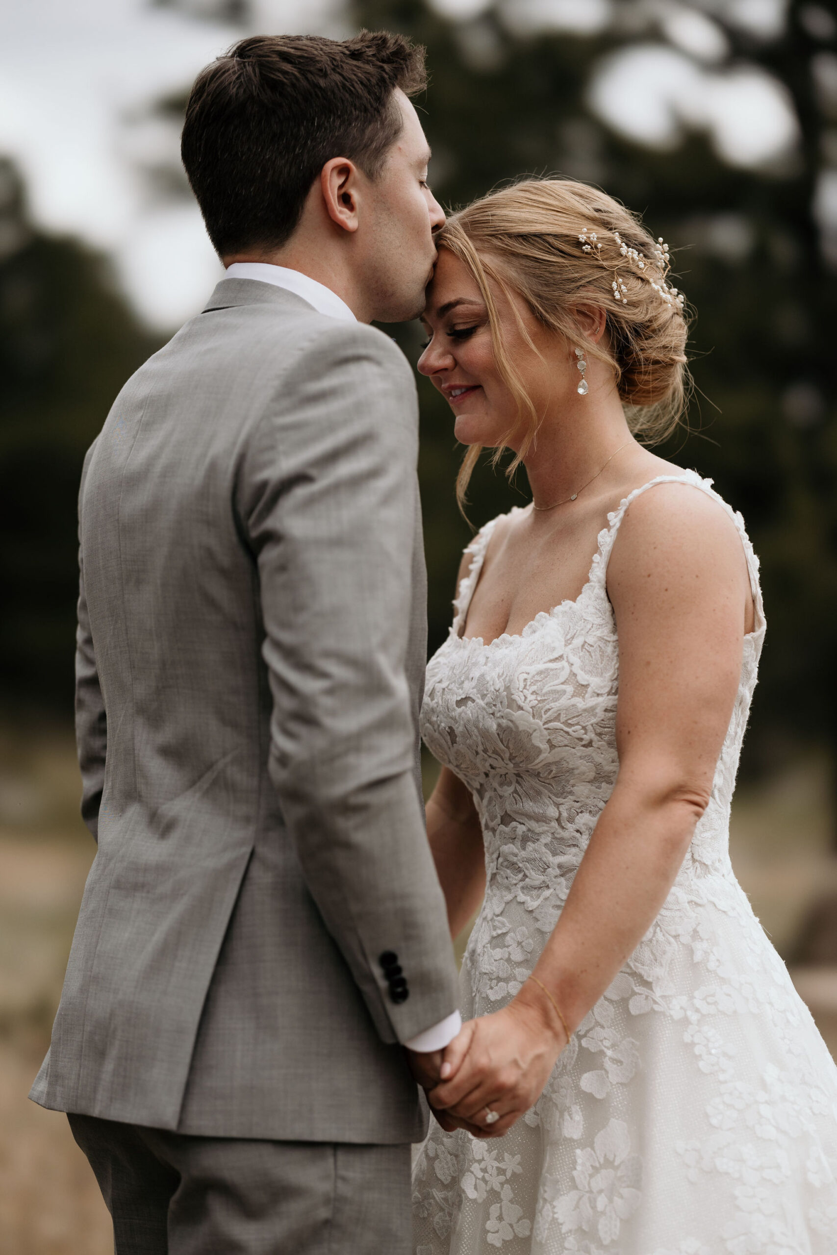 groom kisses brides head during wedding portraits in estes park colorado.