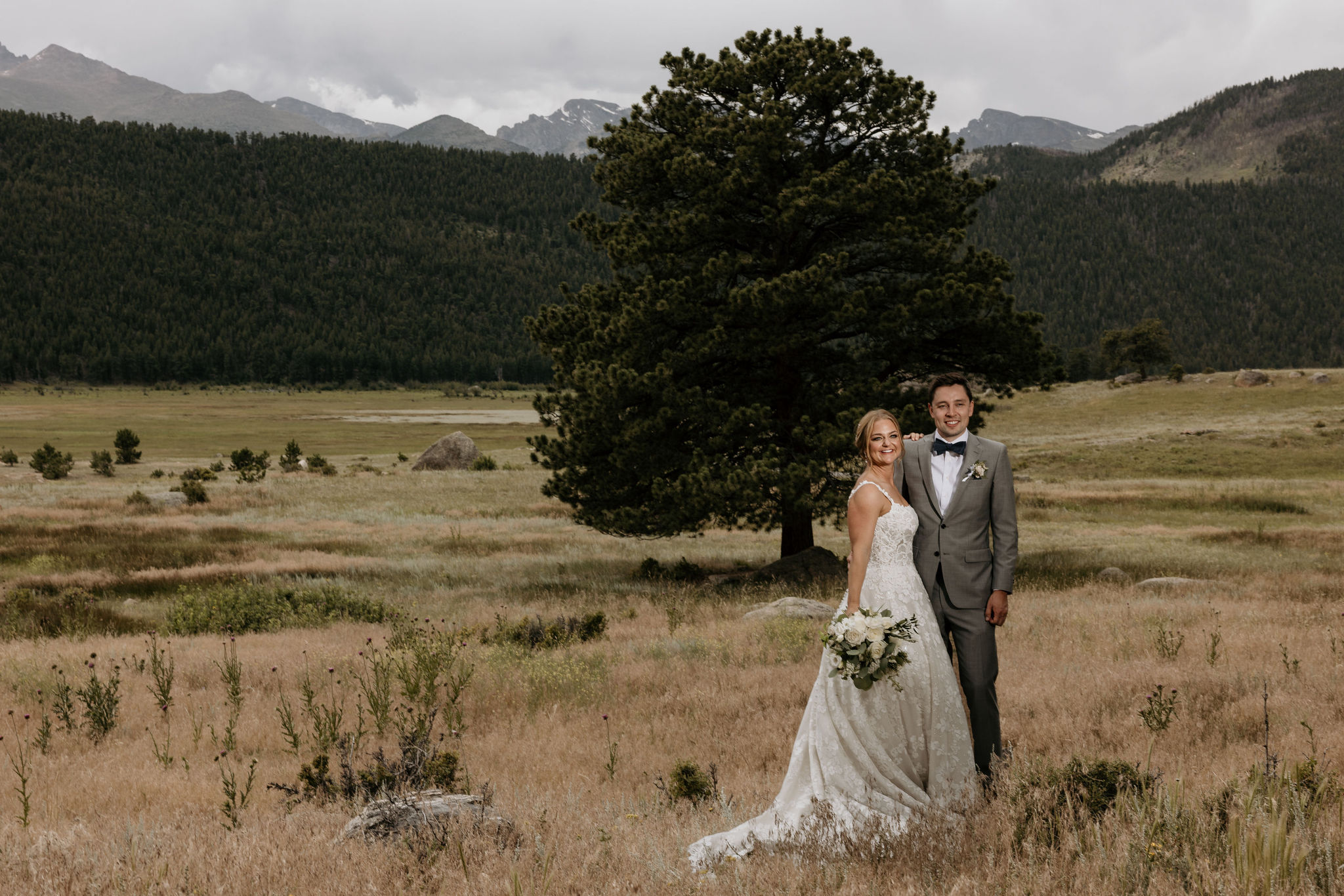 bride and groom stand in front of the rocky mountains during colorado wedding in estes park.