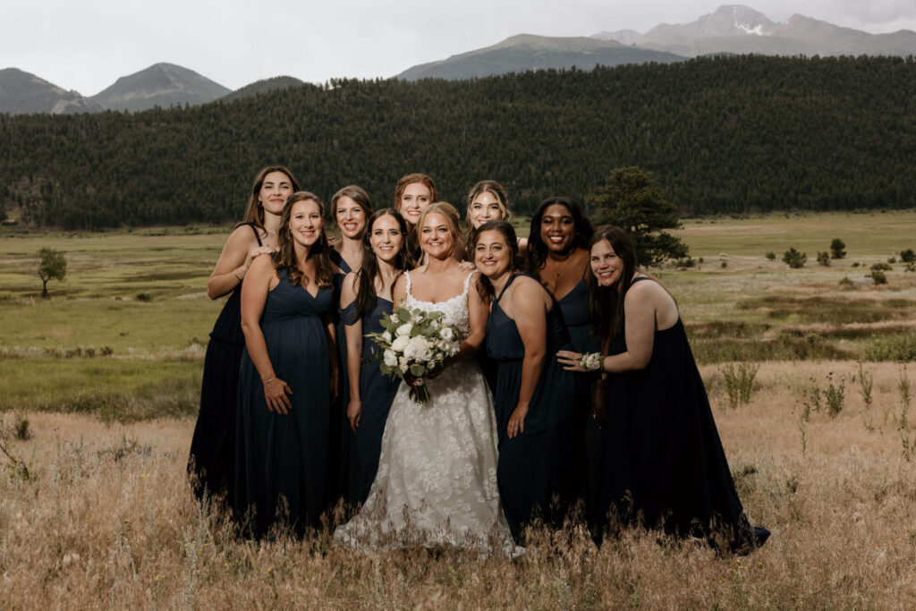 bride and her crew stand in front of rocky mountains during colorado mountain wedding in estes park.