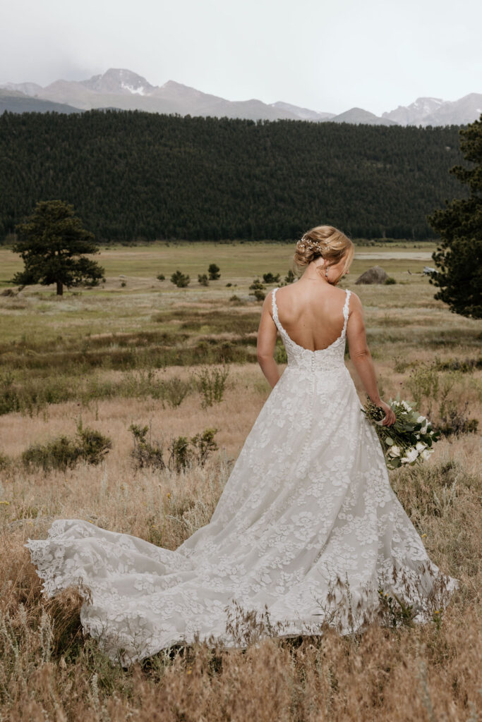 bride stands in front of rocky mountains and faces away during colorado wedding in estes park.
