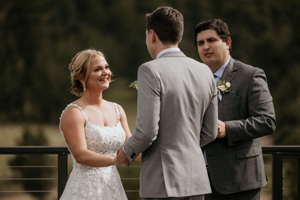 bride and groom smile and look at each other during colorado wedding ceremony at skyview venue in estes park.