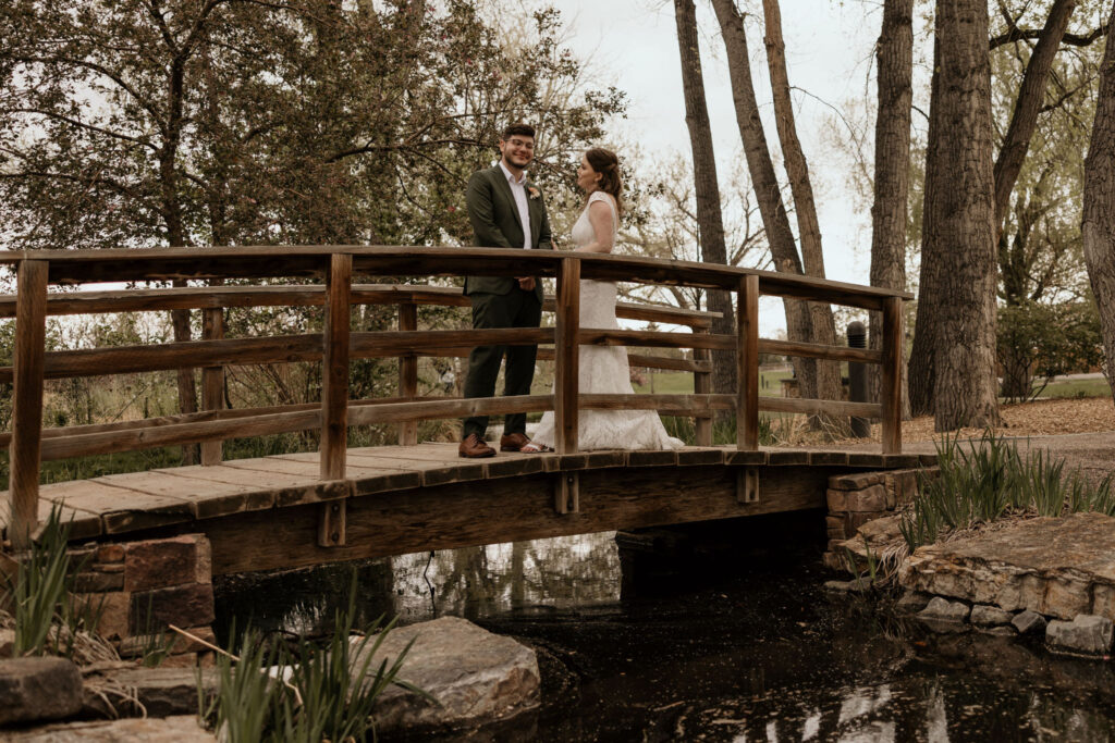 bride and groom stand on wooden bridge in the garden during colorado micro wedding in the spring.