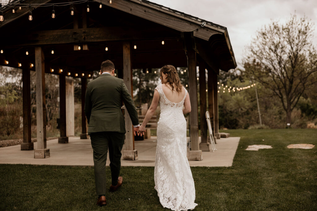 bride and groom walk to lit up pavilion during their colorado minimony.