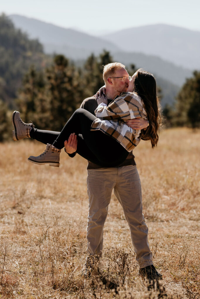 mand holds woman and kisses her after their colorado proposal.