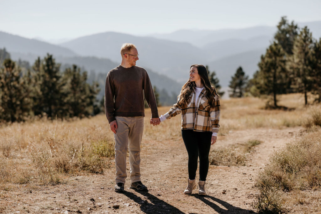 man and woman hold hands in the colorado mountains during engagement photos.