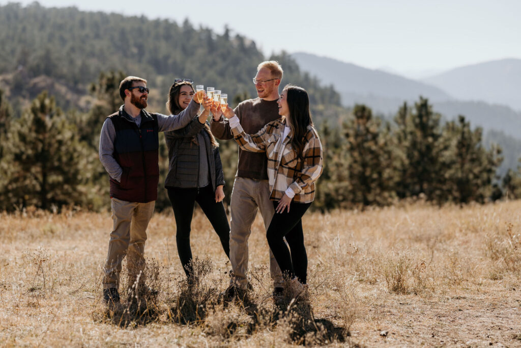 group of friends cheers with champagne during a colorado mountain proposal.
