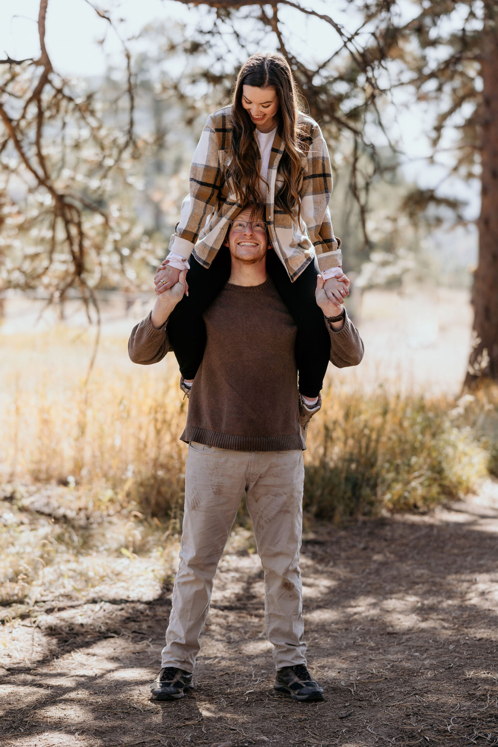 woman sits on mans shoulders during engagement photos.