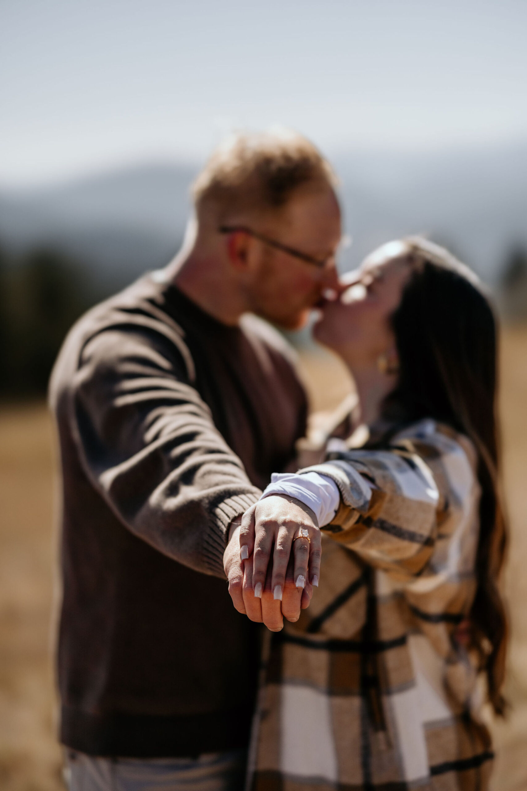couple kisses with hands towards the photographer for colorado engagement pictures after their mountain proposal.