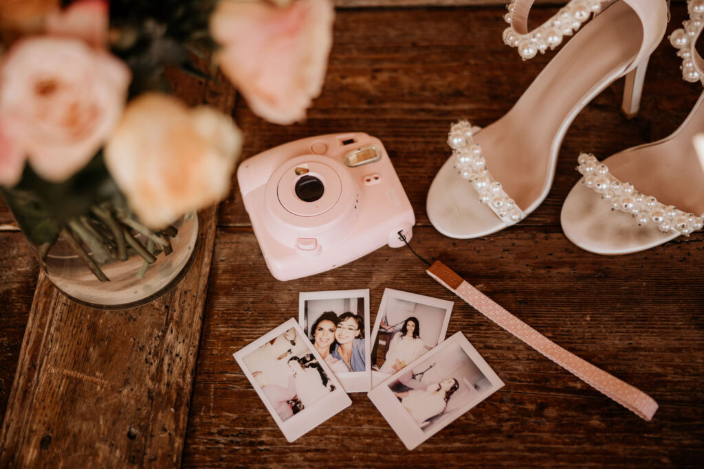 polaroid camera and some photos, along with wedding shoes and florals.