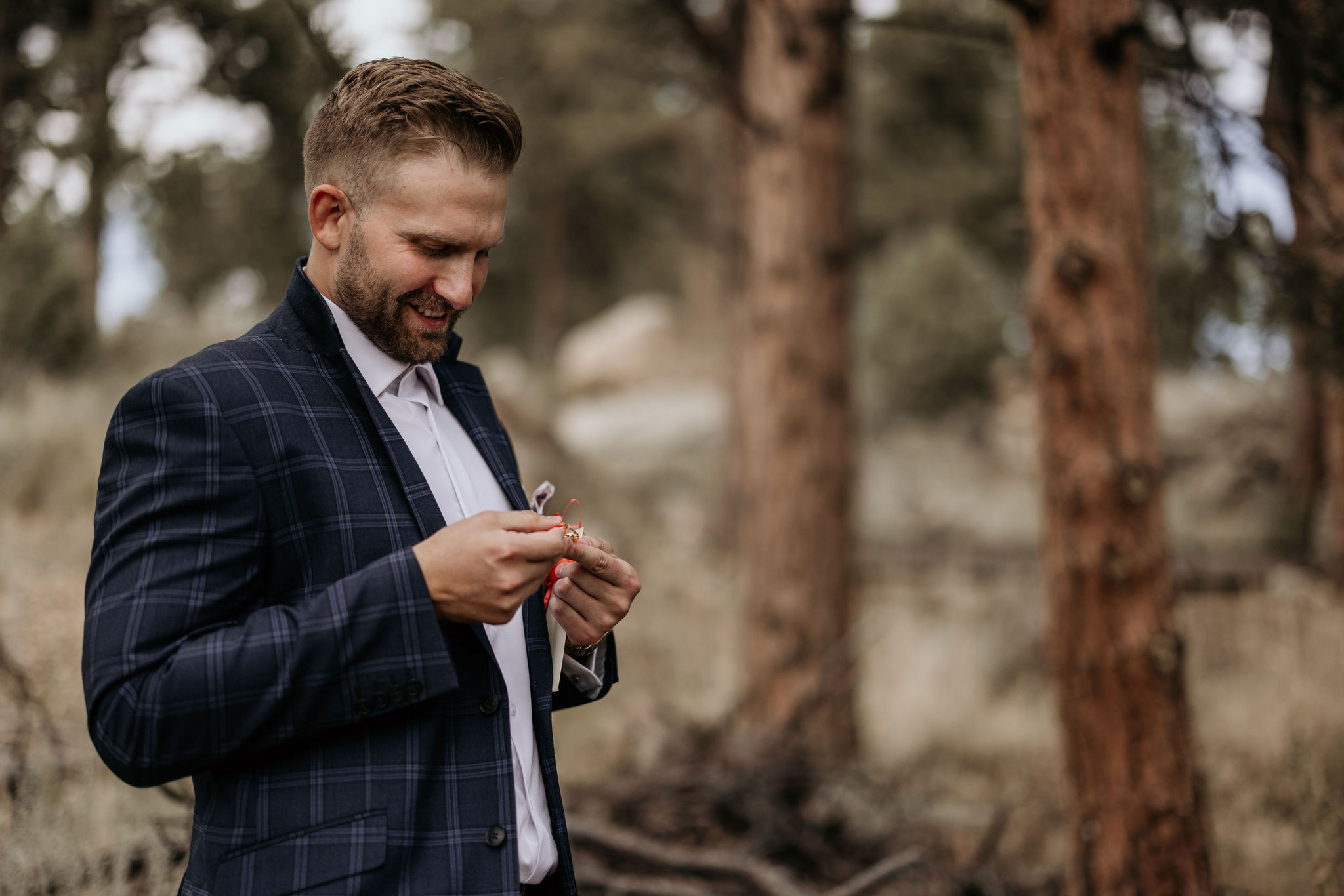 photo of groom standing outside, looking at a gift he got from his wife