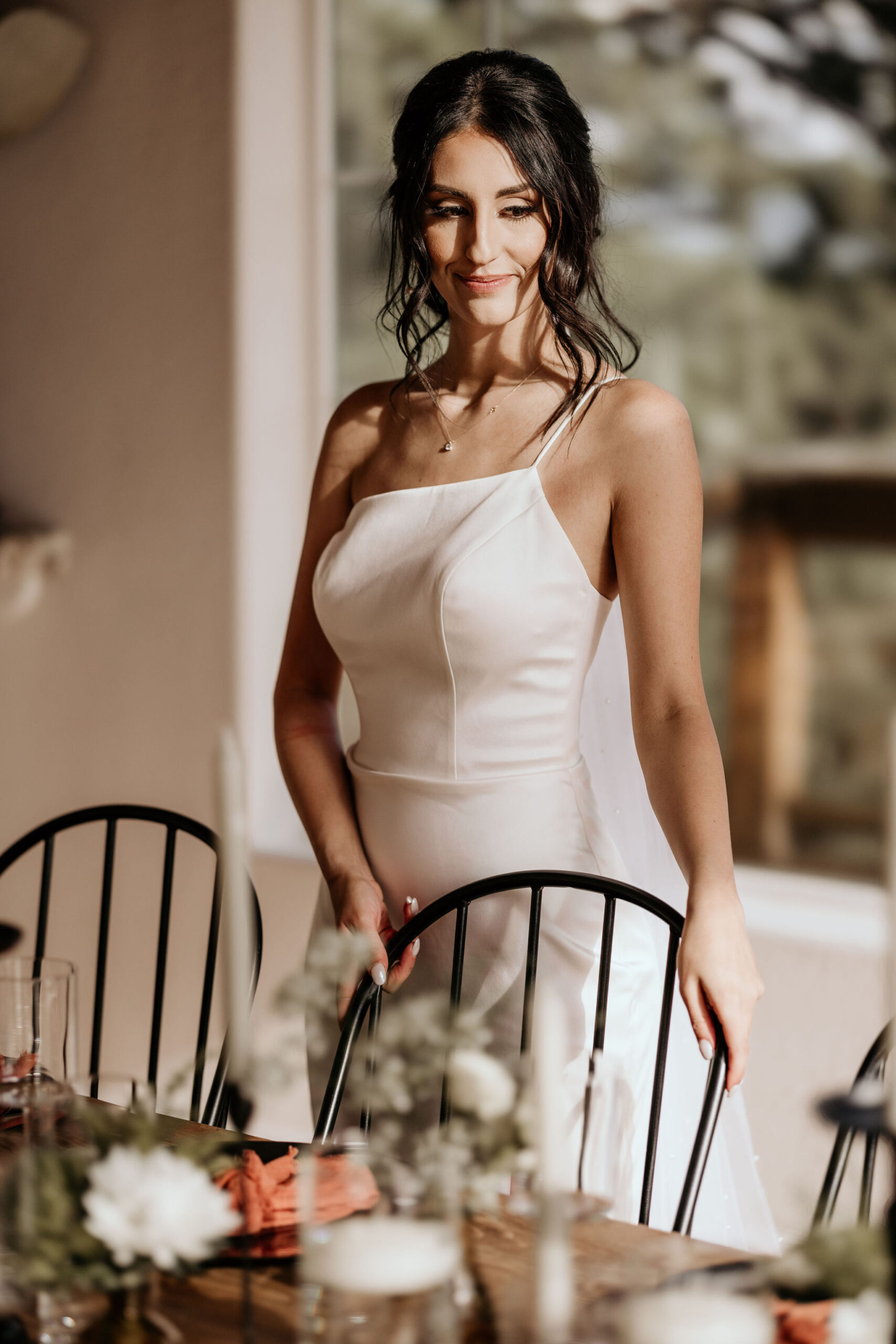 bride stands by family style table during colorado micro wedding reception.