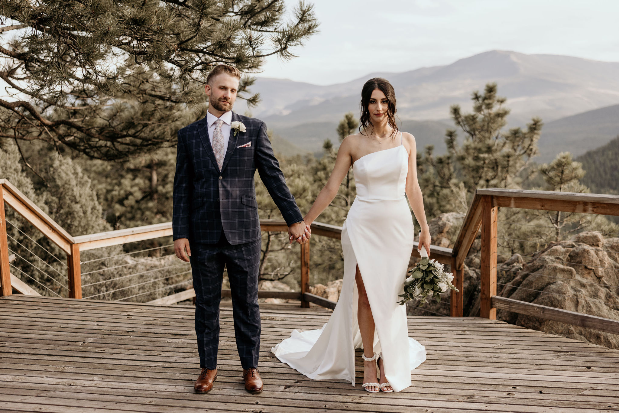 bride and groom pose on deck at airbnb during colorado micro wedding.