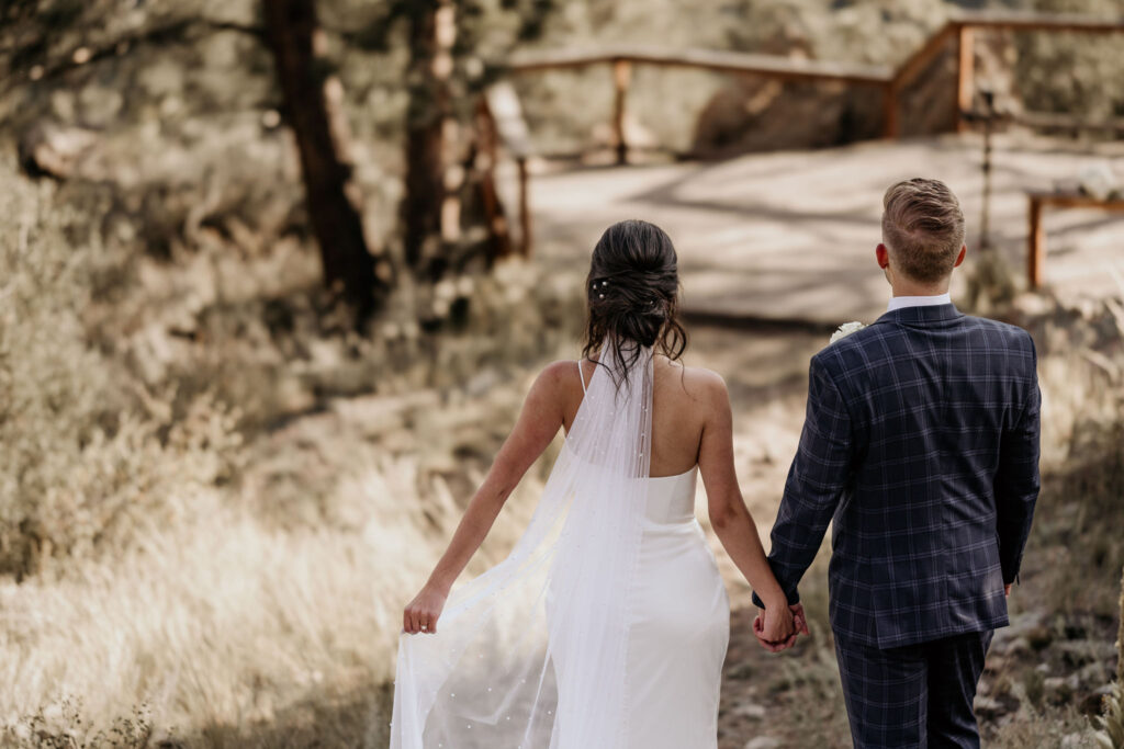 bride and groom walk down trail at airbnb during mountain micro wedding.