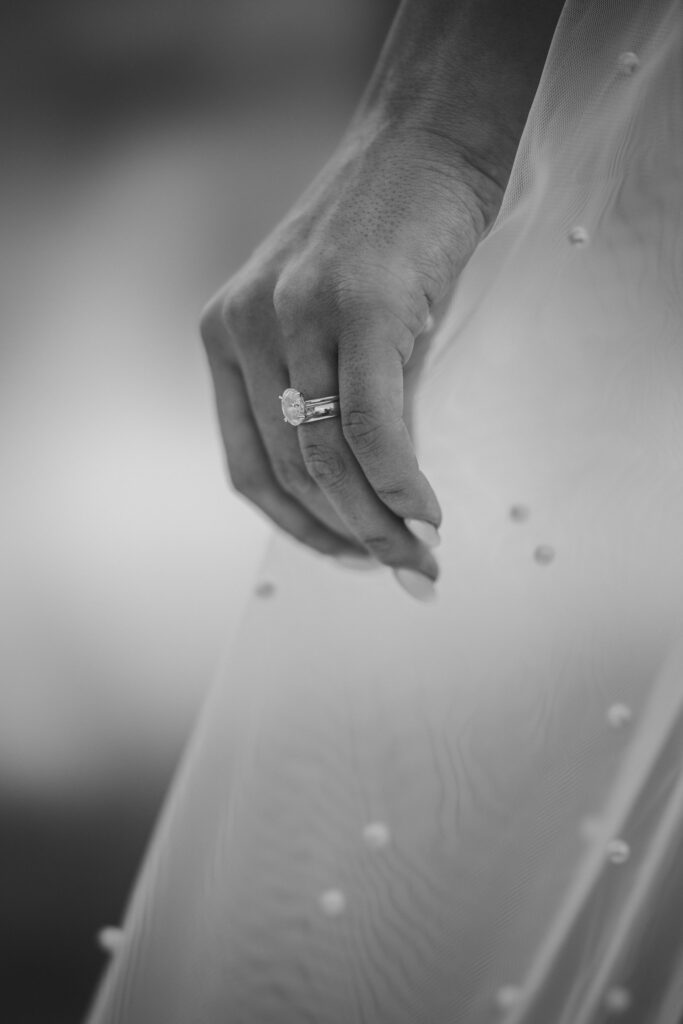 close up image of bride with wedding ring holding her pearl adorned veil.