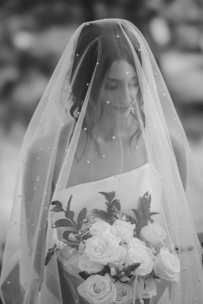 bride poses with veil and bouquet during bridal portraits in colorado.