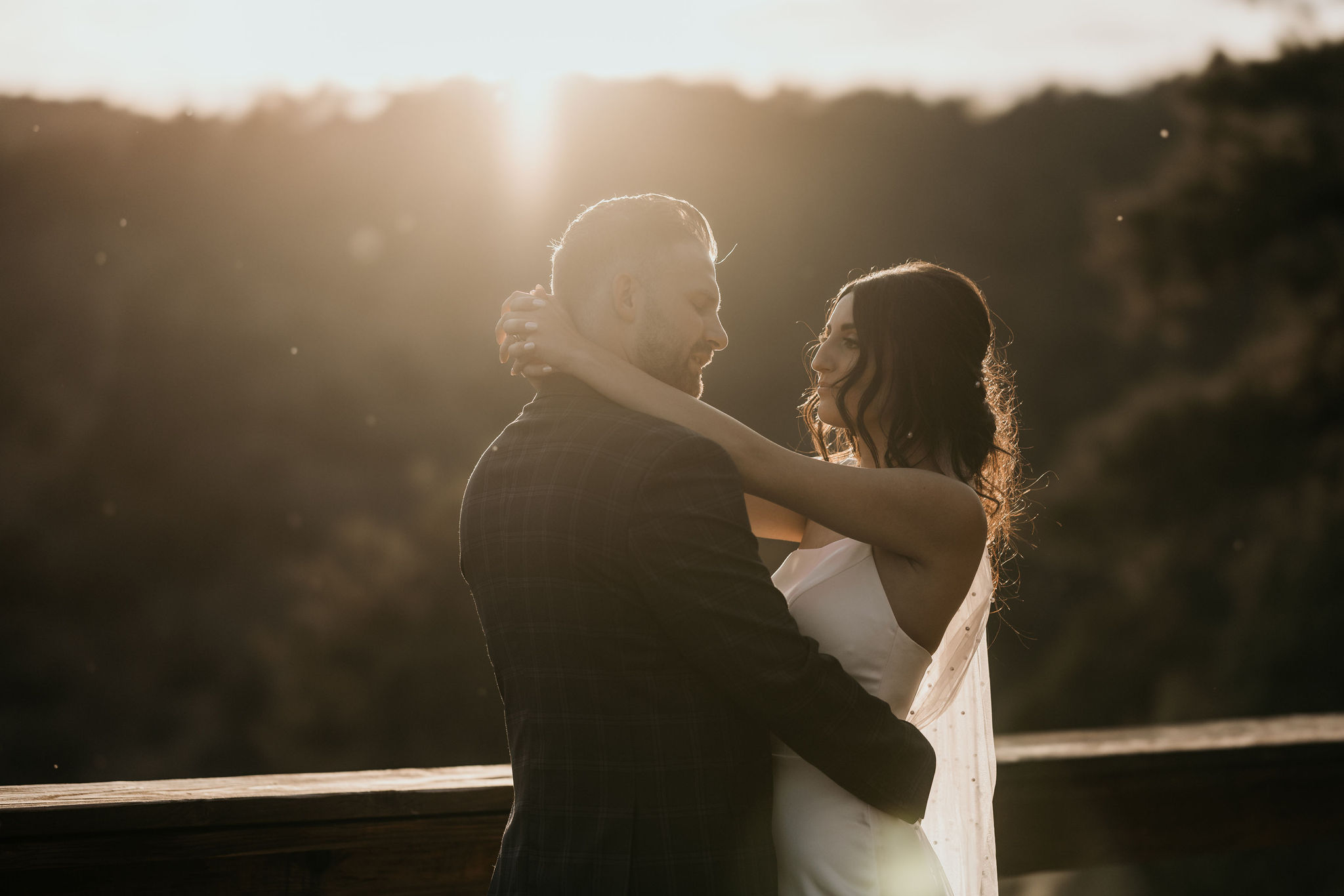 bride and groom embrace and smile at each other during sunset wedding photos