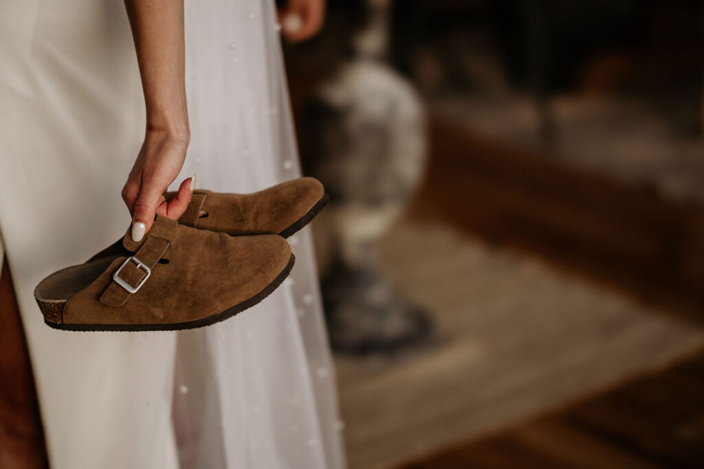 close up image of bride holding her shoes during her airbnb micro wedding.