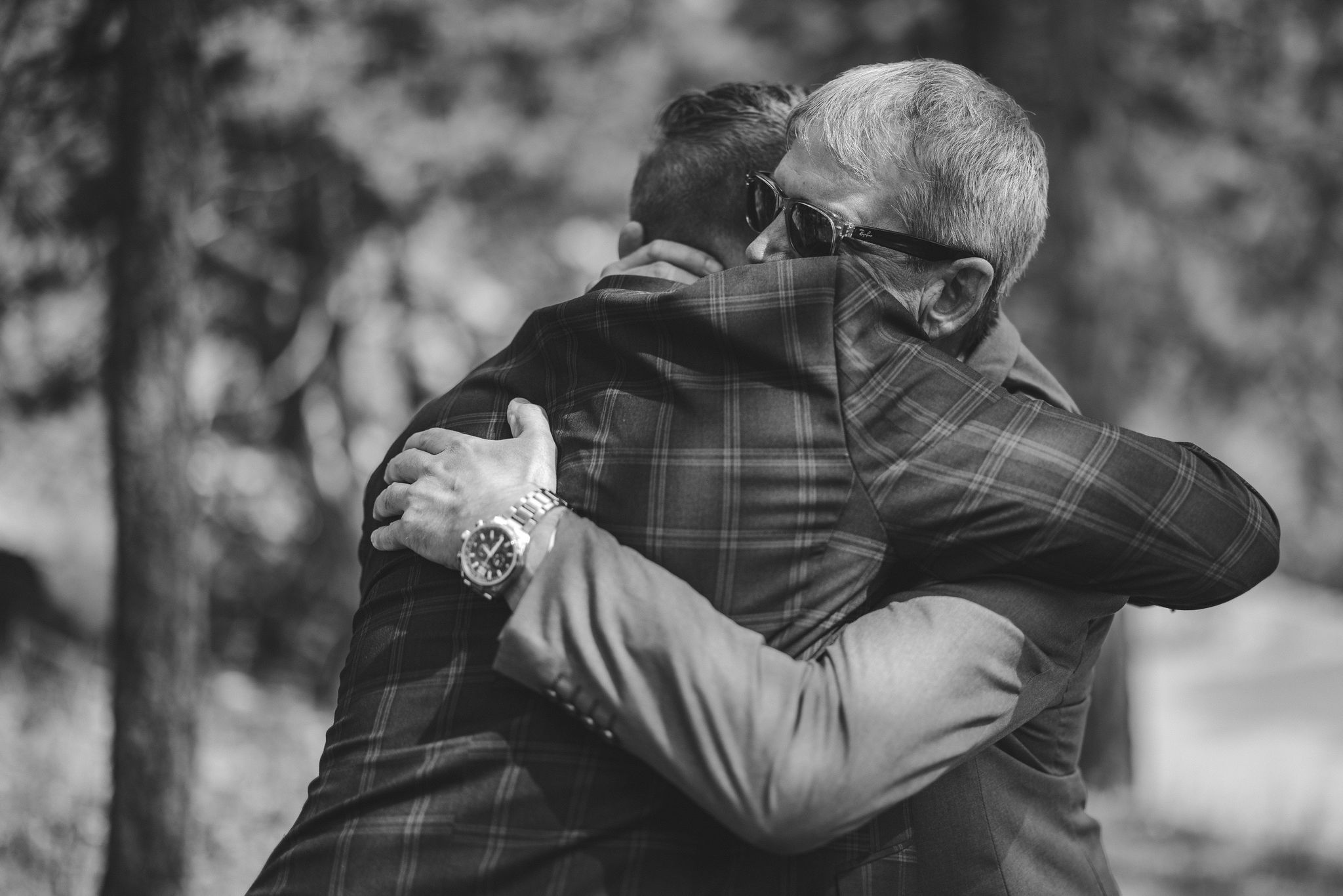 black and white image of the groom and his father hugging before the wedding ceremony
