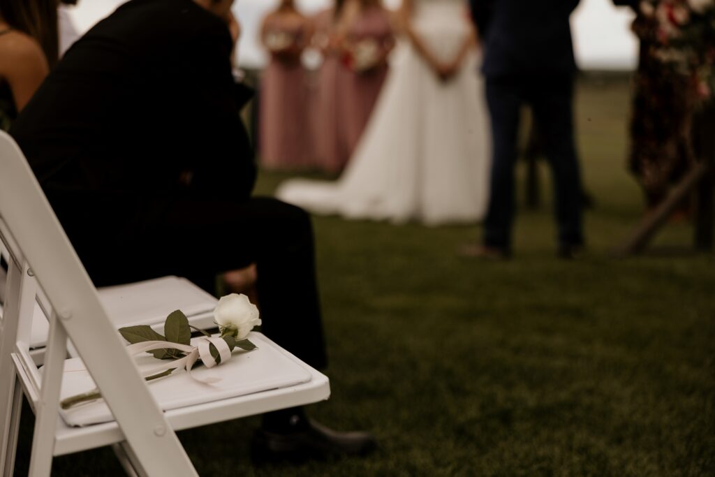 a rose sits on an empty chair, honoring a loved one at a colorado wedding.