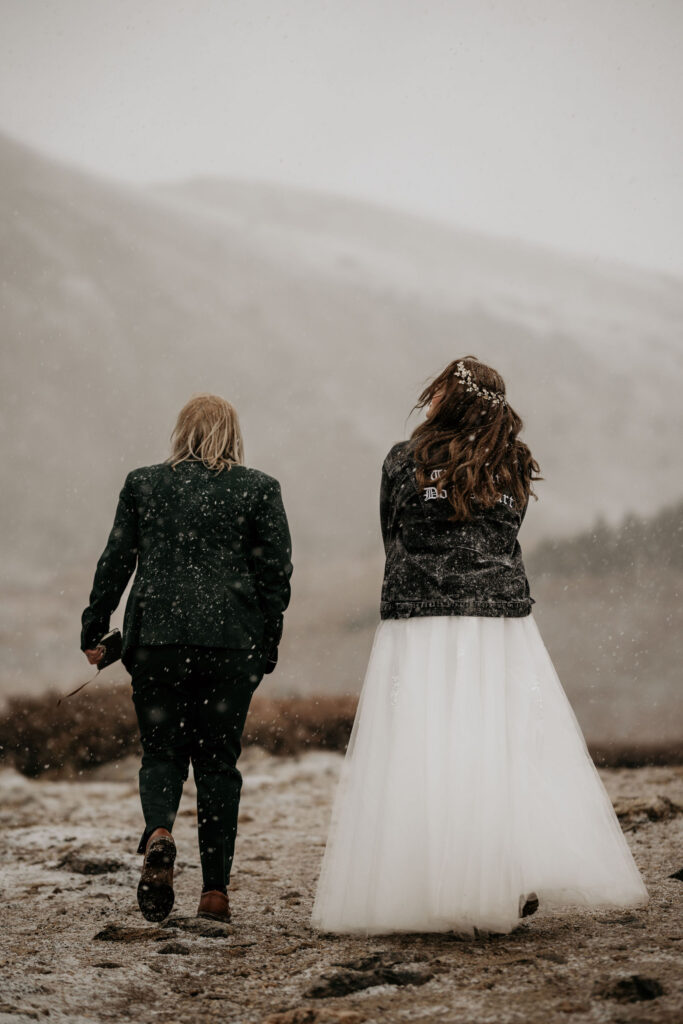 newlywed couple walk in the snow to their breckenridge elopement ceremony.