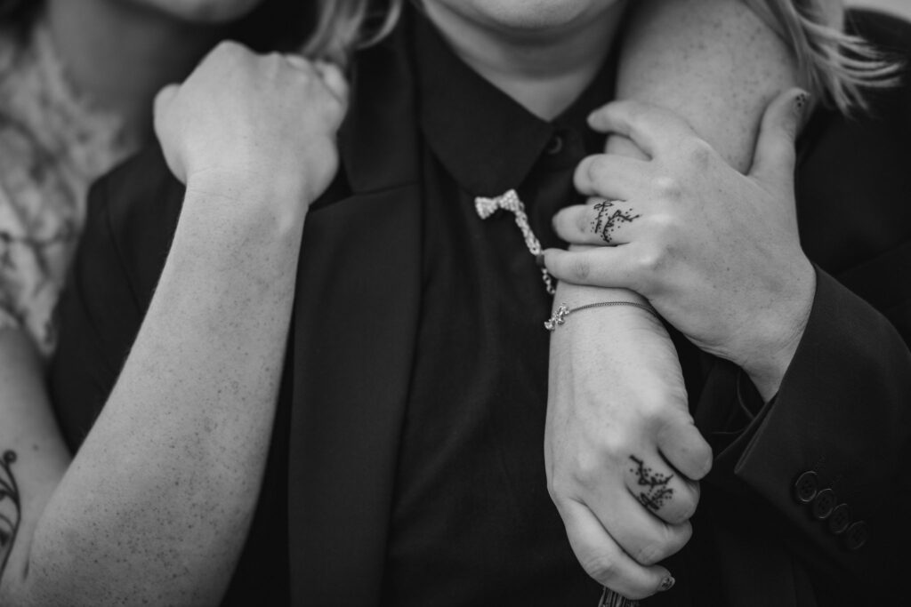 close up image of a newlywed couple with one person putting their arm around the other persons shoulders.