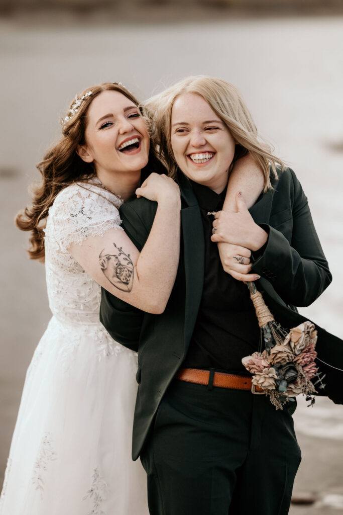 newlywed couple embraces and laughs during LGBTQ+ elopement in colorado.