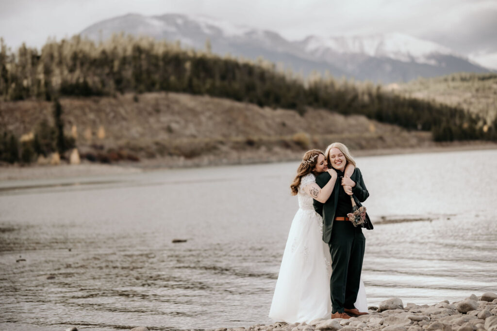 newlywed couple stand at the edge of lake dillon for their breckenridge elopement photos.