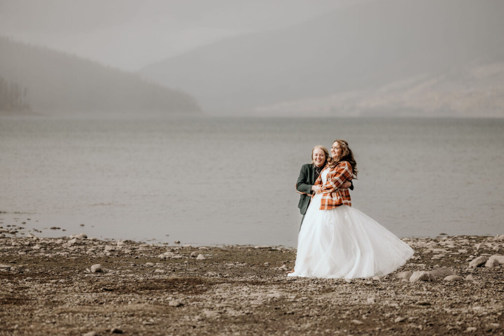 newlywed couple hold each other in front of lake dillon during their breckenridge wedding.