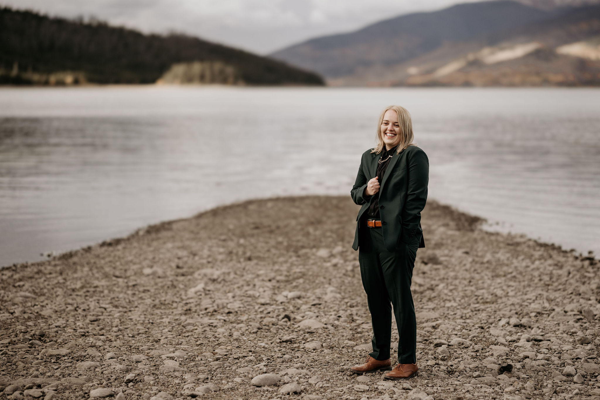person stands on the edge of the lake and smiles for colorado elopement photographer.