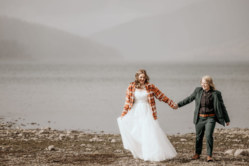 newlywed couple hold hands and walk along dillon reservoir during their colorado elopement.