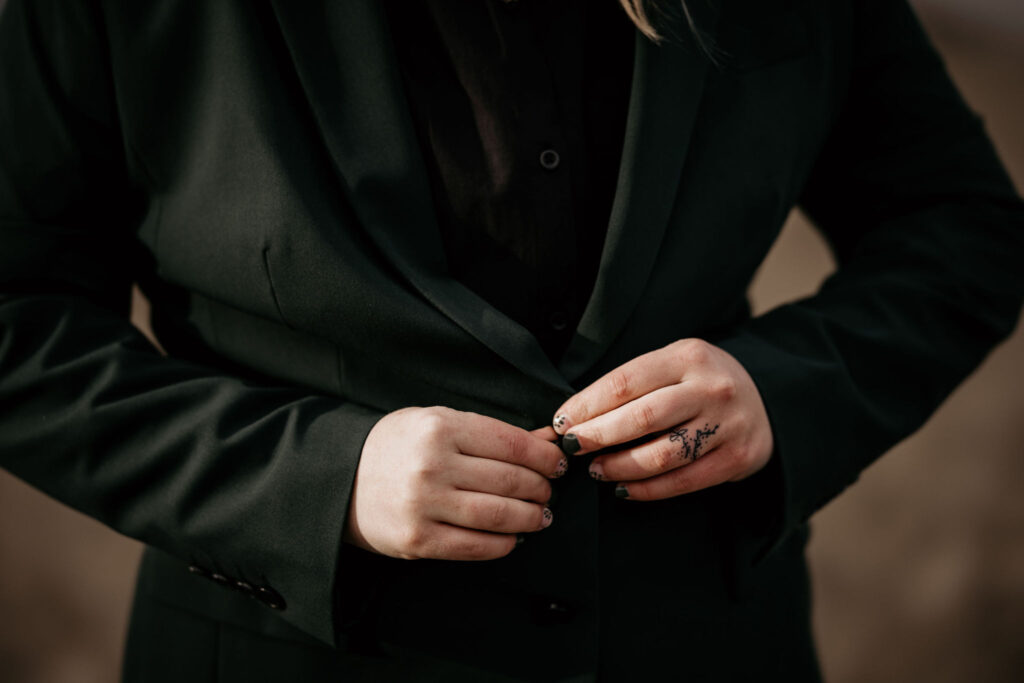 close up image of person buttoning dark green suit during their LGBTQ+ breckenridge elopement.