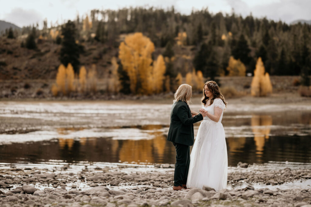 newlywed couple stand in front of yellow aspen trees during their LGBTQ+ wedding in breckenridge colorado.