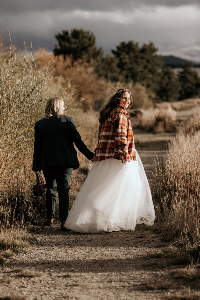 newlywed couple hold hands and walk along trail at Lake Dillon during their LGBTQ+ elopement in breckenridge.