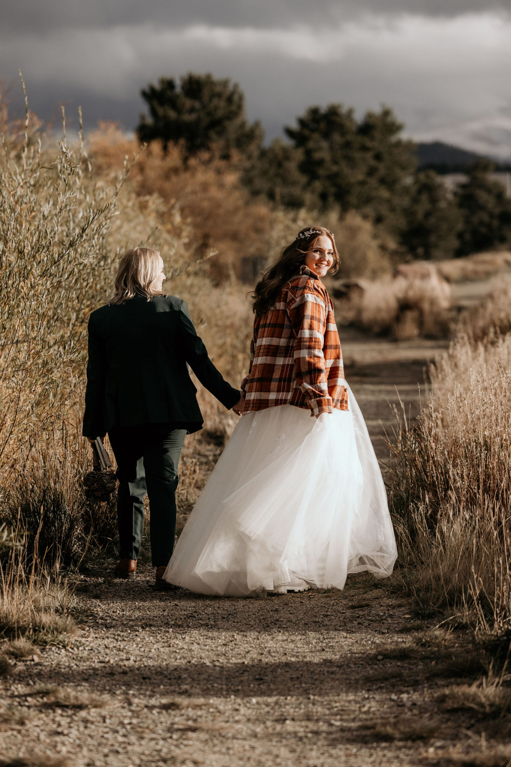 newlywed couple hold hands and walk along trail at Lake Dillon during their simple elopement in breckenridge.